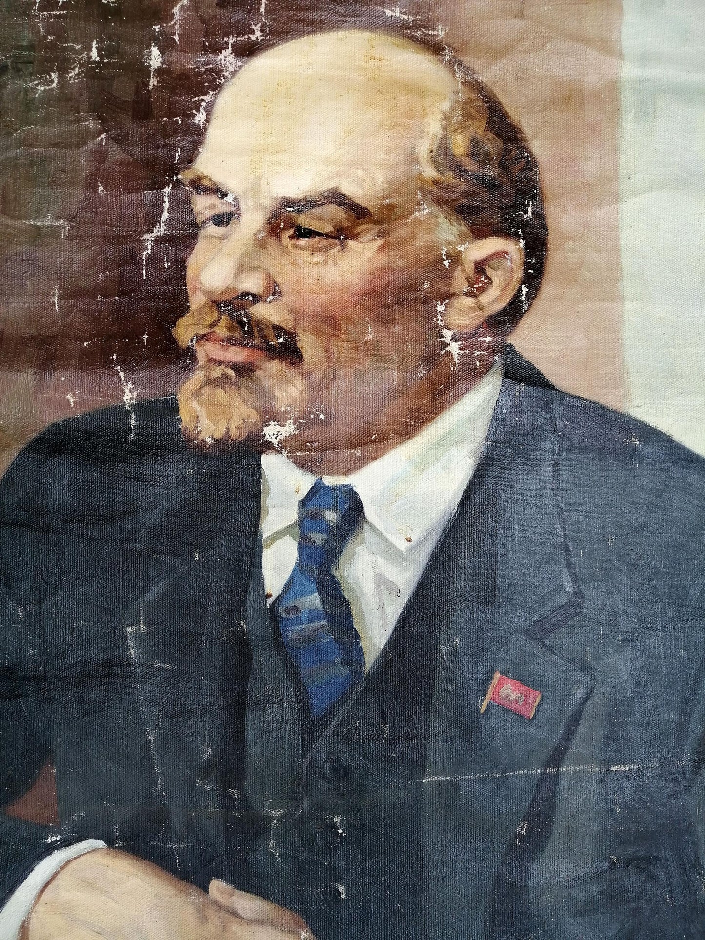 Worn social realism oil portrait of Vladimir Lenin in dark suit and red flag pin
