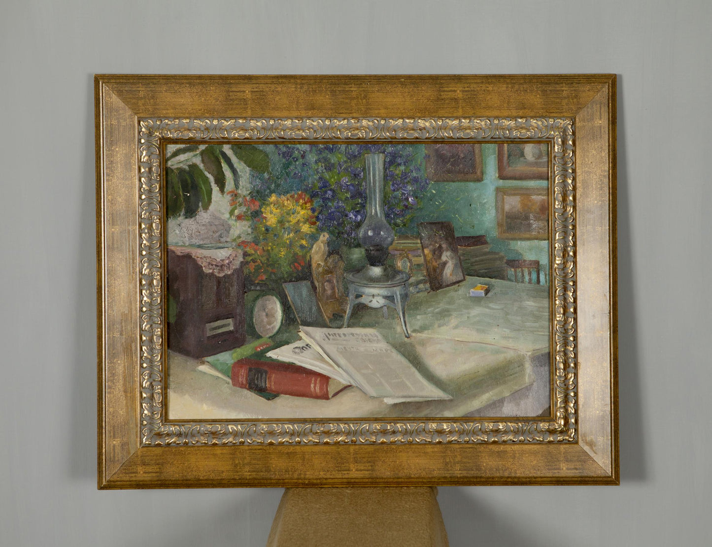 Framed oil painting of still life with books flowers lamp on table
