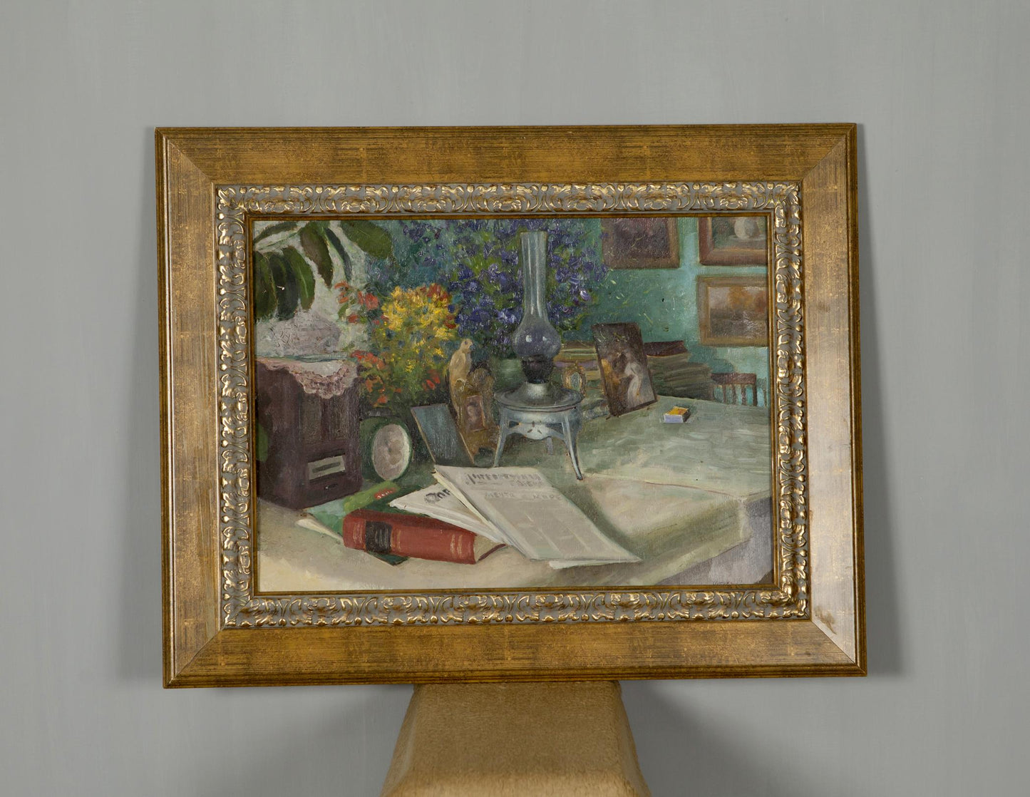 Gold-framed oil painting of still life with vibrant flowers, books, food, drink on table