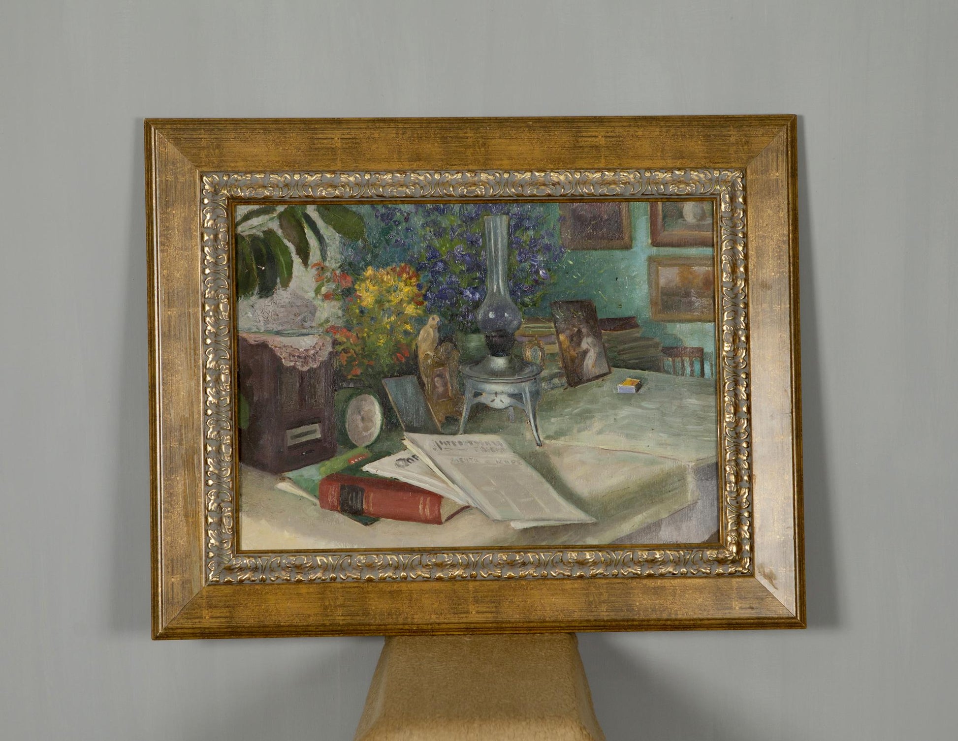 Gold-framed oil painting of still life with vibrant flowers, books, food, drink on table