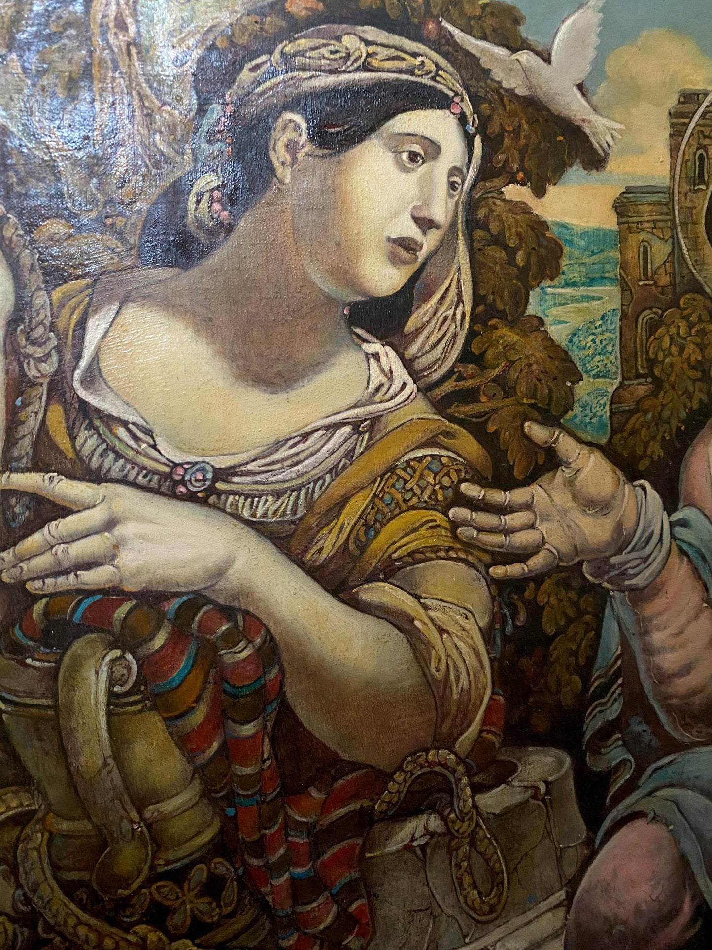A classical oil painting depicts a woman with dark hair adorned in an ornate golden headpiece, wearing a richly detailed garment of gold and white fabric.