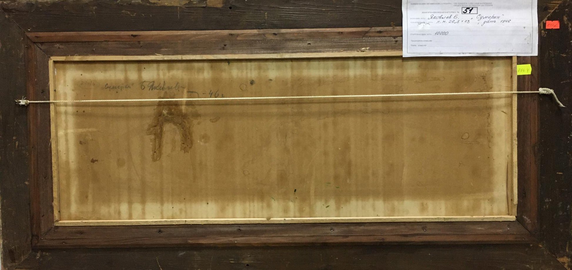 The back of a framed painting with a wooden frame and a beige canvas backing, secured by a thin wire across the top.