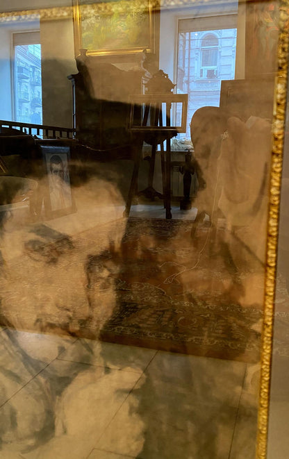Gold-framed mirror reflecting Repin portrait room with furniture